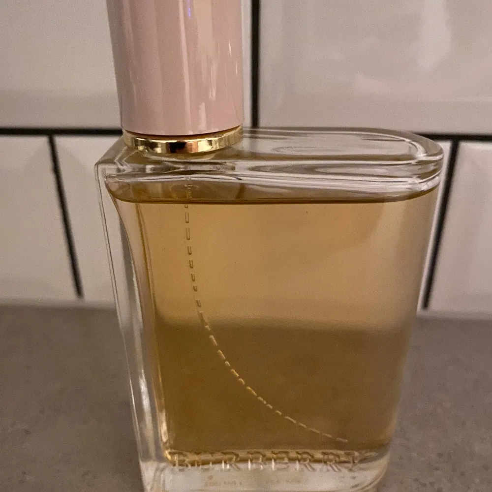 Säljer en lyxig Burberry Her Eau de Parfum i en elegant 100 ml flaska. Parfymen har en stilren design med en genomskinlig glasflaska och en ljusrosa kork. Doften är perfekt för den som vill ha en sofistikerad och modern touch. Flaskan är nästan full och kommer i sin originalförpackning.. Perfume.