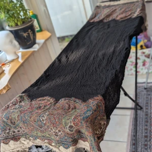 Svart sjal med paisleymönster från India - Säljer en superfin svart sjal med ett detaljerat paisleymönster i rött, blått och grönt. Den är perfekt för höst och vinter, och materialet känns mjukt och skönt mot huden. Endast provad och tvättad.  köpt i Indien  Mycket fint skick,ytuldd förkommer
