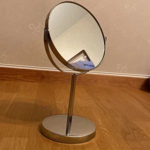 Rund sminkspegel i metall - Säljer en stilren och praktisk rund sminkspegel i metall. Spegeln har en stabil bas och en justerbar vinkel, perfekt för sminkning! Den har en modern design som passar in i de flesta badrum eller sovrum.