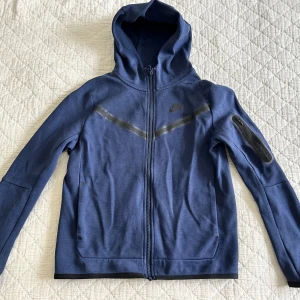 Nike tech set - Blå Nike tech set, storlek L barn 147-158. Tröjan 8/10, byxorna 7/10 pga två mindre defekter som knappt syns. Se bilderna. 