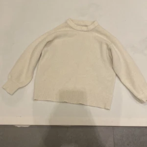 Vit stickad tröja från Zara - Mysig vit stickad tröja från Zara, perfekt för vintern. Tröjan har långa ärmar och en ribbad kant vid ärmslut och nederkant. Enkel och stilren design som passar till många tillfällen.