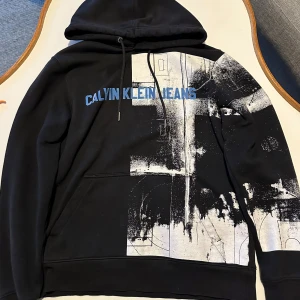 Svart hoodie Calvin Klein  - Snygg svart hoodie från Calvin Klein  med tryck.  väldigt bra skick.