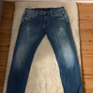 Blå jeans från Replay - Snygga blå jeans från Replay med en klassisk femficksdesign och knappgylf. De har en lätt tvättad look och är perfekta för en avslappnad stil. Märkesdetaljer på baksidan ger en extra touch.