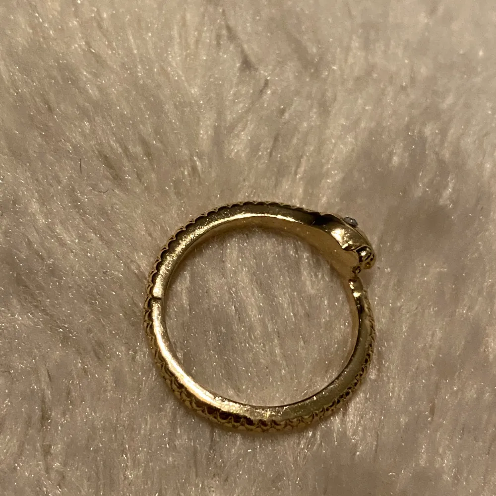 Snygg guldfärgad ring formad som en orm. Ringen har en detaljerad ormdesign med skulpterat huvud och kropp som slingrar sig runt fingret. Perfekt för att ge en unik touch till din stil. Vikt 4 gram . Asusteet.