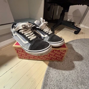 Svarta och vita sneakers från Vans - Säljer ett par sletna klassiska Vans sneakers i svart och vitt. Skorna har en ikonisk design med snörning och en vit sula. Perfekta för en avslappnad stil.