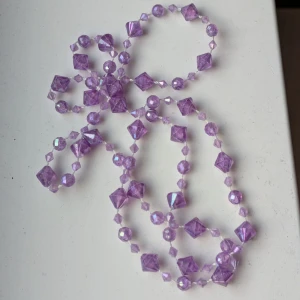 Färgglada pärlhalsband och vit spetschoker - Säljer 3 halsband med två färgglada pärlhalsband och en vit spetschoker. Halsbanden har pärlor i olika former och färger som lila, rosa, grönt och gult. Chokern är i vit spets med justerbart spänne. Perfekt för att liva upp vilken outfit som helst! Alla för 25