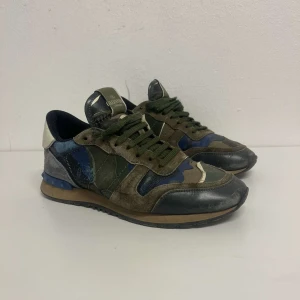 Valentino Rockrunner - Snygga Valentino Rockrunner sneakers med ett coolt camouflagemönster i gröna, blå och beige toner. Skorna är i bra skick, de passar perfekt nu till vintern eftersom de är lite varmare! De är i storlek 41 men passar även 42. Tveka inte på att höra av er av intresse eller minsta fundering!