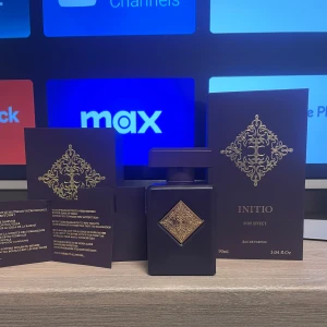 Initio Side Effect Eau de Parfum - Initio Side Effect är en lyxig Eau de Parfum med en djup och förförisk doftprofil. Flaskan är elegant i mörklila med ett gyllene emblem. Doften har varma och kryddiga noter av tobak, rom, kanel och trä, vilket ger en söt och träig karaktär.