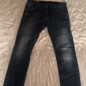 Mörkblå jeans från Donup - Snygga mörkblå jeans från Donup med diskreta slitningar. Jeansen har en rak passform och är perfekta för en avslappnad stil. Detaljer som exempelvis Donups klassiska metalllogga på bakfickan gör byxorna ännu snyggare!