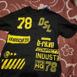 Svart t-shirt med gula tryck - Cool svart t-shirt från Diesel med iögonfallande gula tryck och textdetaljer. Perfekt för en avslappnad stil med en touch av attityd.