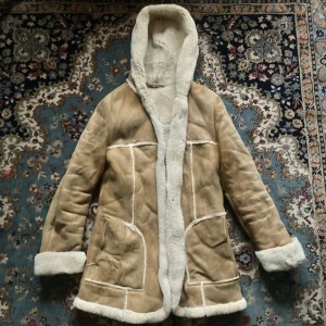 Afghanjacka - Vintage beige pälsjacka i äkta päls från 70-talet. Jackan har långa ärmar är mjukt fodrad vilket gör att den håller värmen utomordentligt bra. Trots att den är äkta vintage är priset lite lägre då skinnet blivit lite missfärgat av åren.