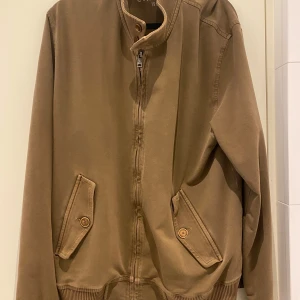 Beige jacka med dragkedja - Säljer en stilren beige jacka med dragkedja och knappar. Jackan har långa ärmar och ribbade muddar vid ärmslut och nederkant. Perfekt för en avslappnad look. Nypris 3500kr. Storleken är Xxl men passar som L