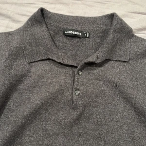 Grå pikétröja från J.Lindeberg - Säljer en stilren grå pikétröja från J.Lindeberg. Tröjan har en klassisk krage med knappar och är långärmad, perfekt för en avslappnad men ändå uppklädd look. Passar bra till både jeans och chinos. Det står att den är XL men passar verkligen inte det skulle säga att den motsavarar M - S så för dig runt 170 - 180.