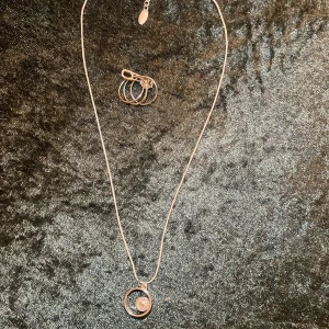 Silverhalsband med cirkelhänge - Elegant silverhalsband med ett cirkelhänge som har en glittrande detalj i mitten. Kedjan är tunn och justerbar med ett litet hänge vid låset. Perfekt för att ge en stilren touch till din outfit.