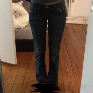 Blå bootcut jeans - Snygga blå bootcut jeans med låg midja. Perfekta för en avslappnad stil. Klassisk design med fem fickor och knappgylf.