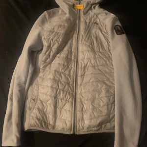 Grå quiltad jacka från parajumper  - Säljer en snygg grå quiltad jacka från parajumper. Den har en dragkedja framtill och är perfekt för kyliga dagar. Jackan är i mycket bra skick och har en stilren design med en luva. Perfekt för både vardag och utomhusaktiviteter!Nypris 6500kr