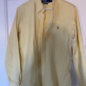 Gul skjorta från Polo Ralph Lauren - Säljer en snygg gul skjorta från Polo Ralph Lauren i storlek S. Skjortan är slim fit och har långa ärmar med knappar. Perfekt för både vardag och festliga tillfällen. Den är i mycket bra skick och redo för en ny ägare!