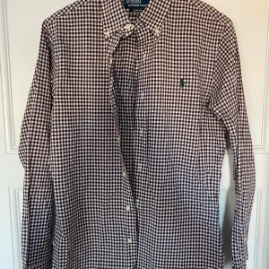 Rutig skjorta från Polo Ralph Lauren - Säljer en snygg rutig skjorta från Polo Ralph Lauren i brunt och vitt. Skjortan är i slim fit och har långa ärmar med knappar. Perfekt för både vardag och fest! 🕺