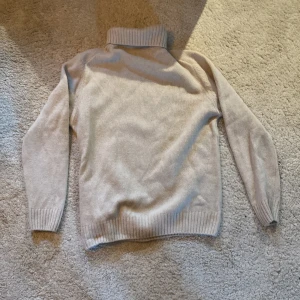 Beige polotröja från Zara - Säljer en supermysig beige polotröja från Zara. Perfekt för kyliga dagar med sin mjuka och varma känsla. Tröjan har långa ärmar och ribbade kanter vid ärmslut och nederkant. Passar som en medium/large