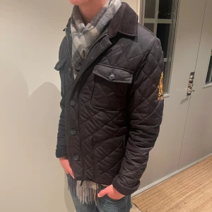Svart quiltad jacka från Morris - Säljer en snygg svart quiltad jacka från Morris i storlek medium. Jackan har knappar framtill. Perfekt för höst och vår med sin stilrena design och bekväma passform. Den har också en broderad detalj på ärmen.  🔶Priset går och sänka vid snabb affär.