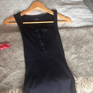 Mörkblå ärmlös topp  - Snygg och Sexy mörkblå ärmlös topp i ett stretchigt material. Toppen har knappar framtill och en enkel design som passar perfekt till både vardag och fest. Perfekt för sommardagar eller som ett basplagg i garderoben.