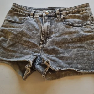 Grå jeansshorts från H&M - Säljer ett par grå jeansshorts från H&M i mycket bra skick. De är lågmidjade med en snygg slitning vid benen för en avslappnad look. Perfekta för sommardagar eller festivaler! 🕶️