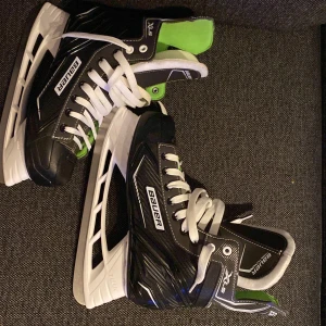 Svarta skridskor från Bauer - Säljer ett par svarta skridskor från Bauer i mycket bra skick. De har en snygg design med vita snören och gröna detaljer på insidan. Perfekta för vinterns isäventyr! 🏒 Använda cirka 2 ggr 