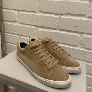 Beige sneakers från Jim Rickey - Säljer ett par snygga beige sneakers från Jim Rickey i mocka. De har en klassisk design med snörning och en vit sula. Perfekta för både vardag och fest! 🕺