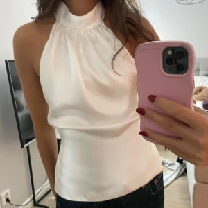 Vit halterneck topp - Säljer en superfin vit halterneck topp med knytning i ryggen. Perfekt för sommardagar eller en utekväll. Toppen är ärmlös och har en elegant, enkel design som passar till både jeans och kjol. Den är i mycket bra skick och redo för nya äventyr! Köpt från zara