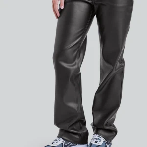 Svarta läderbyxor från BikBok - Säljer ett par svarta läder-byxor från BikBok i storlek 36. Byxorna har en loose passform och är perfekta för en trendig look. De är tillverkade i syntetmaterial och har en stilren design medföljande extraknapp ifall den skulle gå sönder. Perfekta för höst och vinter då dem är varma, säljer då de inte är min stil. Skriv för fler bilder💗