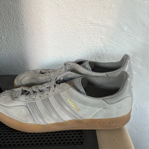 Grå Adidas Gazelle sneakers - Säljer ett par grå Adidas Gazelle sneakers i mocka. .Perfekta för vardagsbruk . De är i bra skick men använda ett par gånger.storlek 43/1/13 men passar även bra till 44,hör gjärna av er om frågor(priset går att sänka vid en snabb affär)!