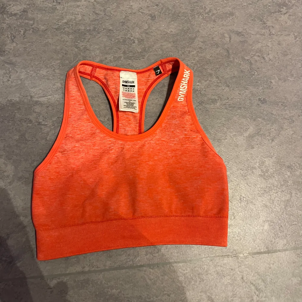 Säljer en snygg röd sport-bh från Gymshark i storlek XS. Den är perfekt för träning med sin bekväma passform och stretchiga. Den är använd endast en gång och i mycket bra skick!. Toppar.