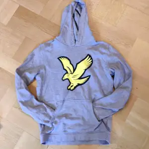 Säljer en snygg grå hoodie från Lyle & Scott med en cool gul örn på framsidan. Perfekt för både vardag och chill. Den är i bra skick och superbekväm med en klassisk passform. Perfekt för höst och vår! Motsvarar xs I storlek 