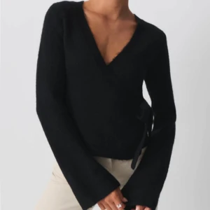 Stickad tröja (omlottkofta)  - Säljer en mysig svart omlottkofta i mycket bra skick. Den har en v-ringad design och långa ärmar, perfekt för höst och vinter. Koftan har en knytning i sidan som ger en snygg passform. Jag är 172 och har storlek M (knappst använd o köpte för 400) 