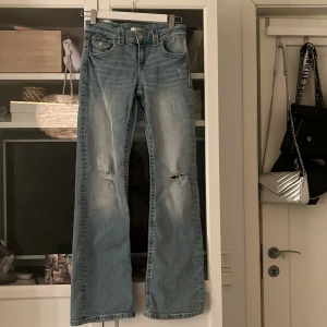 Blå jeans från Gina Tricot - Snygga blå jeans från Gina Tricot med slitningar på knäna. De har en klassisk femficksdesign och knappgylf. Perfekta för en avslappnad stil med en touch av edge. Kom privat för fler bilder eller frågor 💕