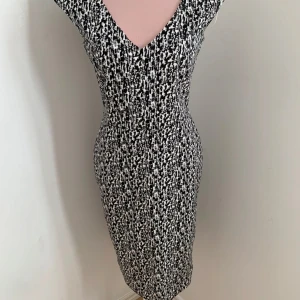 Svartvit mönstrad klänning - Snygg svartvit klänning med ett unikt mönster och v-ringad hals. Perfekt för att sticka ut med stil. Klänningen har en tight passform som framhäver figuren.