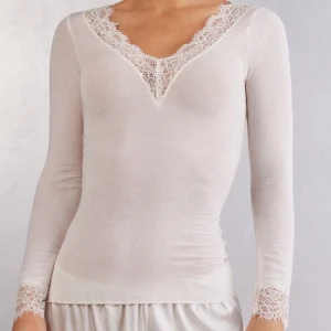 Vit intimissimi topp med spetsdetaljer - Helt ny från INTIMISSIMI! Kan även tänka mig byta denna vara till annan färg. Vit topp med långa ärmar och v-ringning, dekorerad med spetsdetaljer vid hals och ärmslut. Perfekt för en stilren look.