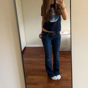 Mörkblå t-shirt med tryck  - Säljer en mörkblå t-shirt från in print er trust med ett coolt discokultryck i vitt på framsidan. Perfekt för dig som vill sticka ut med en unik stil. T-shirten har korta ärmar och en normal passform. Texten 'In Print We Trust' finns tryckt bredvid discokulan.