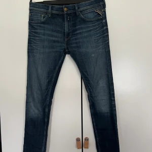 Mörkblå jeans från Replay - Snygga mörkblå jeans från Replay med en klassisk femficksdesign. De har en dragkedja och knapp framtill samt diskreta slitningar för en trendig look. Perfekta för en avslappnad stil.