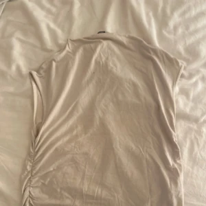 Beige t-shirt - Säljer en enkel och stilren beige t-shirt med korta ärmar. Perfekt för en avslappnad look.