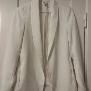 Vit kavaj från Ambition - Elegant vit kavaj från Ambition med en stilren design. Kavajen har långa ärmar och en klassisk krage, perfekt för en sofistikerad look. Passar utmärkt till både formella och avslappnade tillfällen.