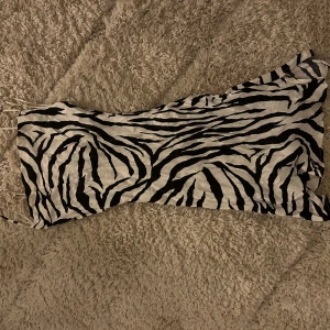 Zebramönstrad klänning - Snygg zebramönstrad klänning med smala axelband. Perfekt för en djärv look. Klänningen har en figurnära passform och är i en kort längd.