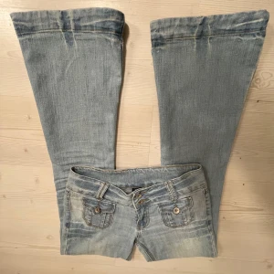 Ljusblå bootcut jeans - Snygga ljusblå bootcut jeans med dubbla knappar och fickor med lock fram och bak. Midjemåttet 39, Innerbenslängd 81, Ytterbenslängd 102 och grenmåttet 19. Jag är 167💗