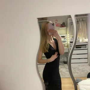 Svart klänning med rynkad detalj på baksida - Snygg svart klänning från NLY One i storlek S. Klänningen har en elegant rynkad detalj på baksidan och är ärmlös med en lång v-ringning. Perfekt för en kväll ute eller en speciell tillställning. 