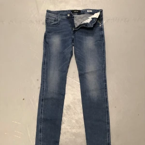 Blå jeans från Replay - Snygga blå jeans från Replay med en klassisk femficksdesign. De har en dragkedja och knapp framtill. Jeansen har en lätt tvättad look som ger en avslappnad stil. Perfekta för en casual look. Helt oanvända (nypris 1800kr) Storlek: 29W 32L