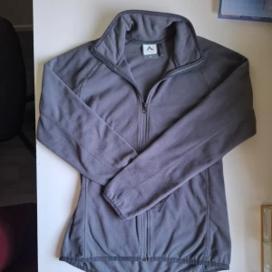 Grå fleecejacka från McKinley - Säljer en grå fleecetröja från McKinley. Den är perfekt för kyliga dagar nu il höst. Tröjan har en dragkedja framtill och en hög krage för extra skydd mot vinden. Den är långärmad och har en enkel, stilren design. Den är använd fåtal gånger och har inga defekter. Skriv om du har frågor! Priset är diskuterbart. <3