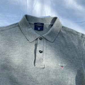 Gant piké grå - Sällan använd och väl omhändertagen. Tidlös pikétröja från GANT. Varumärket är starkt förknippat med amerikansk preppystil och klassiska plagg med influenser hämtade från IVY-League universitet Yale, New Haven.                       Butik pris: 999kr