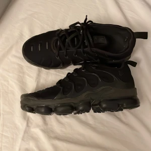 Svarta Nike sneakers - Säljer ett par svarta Nike Air Max sneakers i bra använt skick. De har en cool design med snörning och en robust sula som ger bra grepp. Perfekta för både vardag och träning!