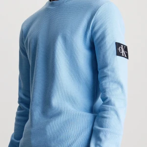 Ljusblå tröja från Calvin Klein - Säljer en stilren ljusblå tröja från Calvin Klein. Den är långärmad och har en snygg logga på ärmen. Perfekt för både vardag och lite finare tillfällen. Tröjan är i ett mjukt och bekvämt material som känns skönt mot huden.