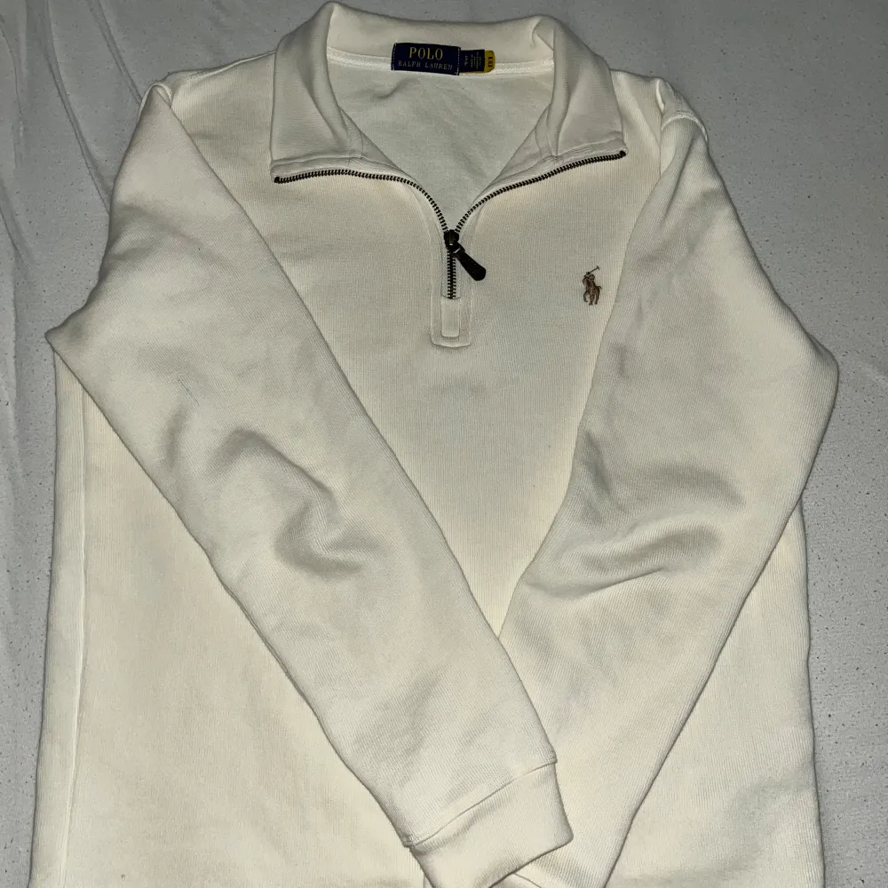 Säljer en stilren beige tröja från Ralph Lauren. Den har en dragkedja vid halsen och det klassiska Ralph Lauren-logotypen broderad på bröstet. Perfekt för en avslappnad men ändå snygg look.. Tröjor & Koftor.